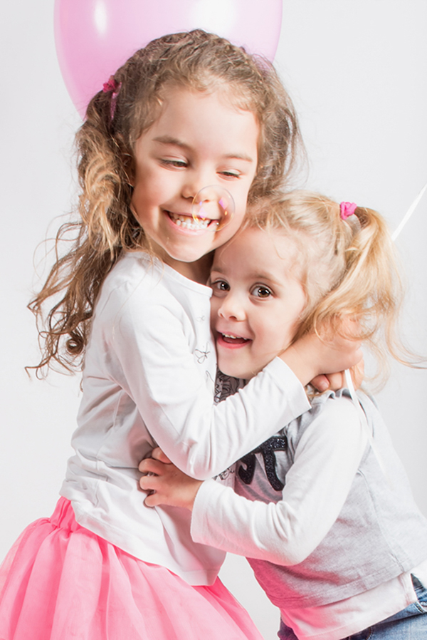 foto in primo piano di due bambine sorelle che si abbracciano felici