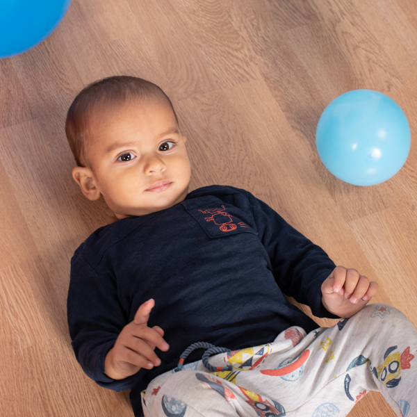foto di un bimbo sdraiato per terra con palloncini intorno