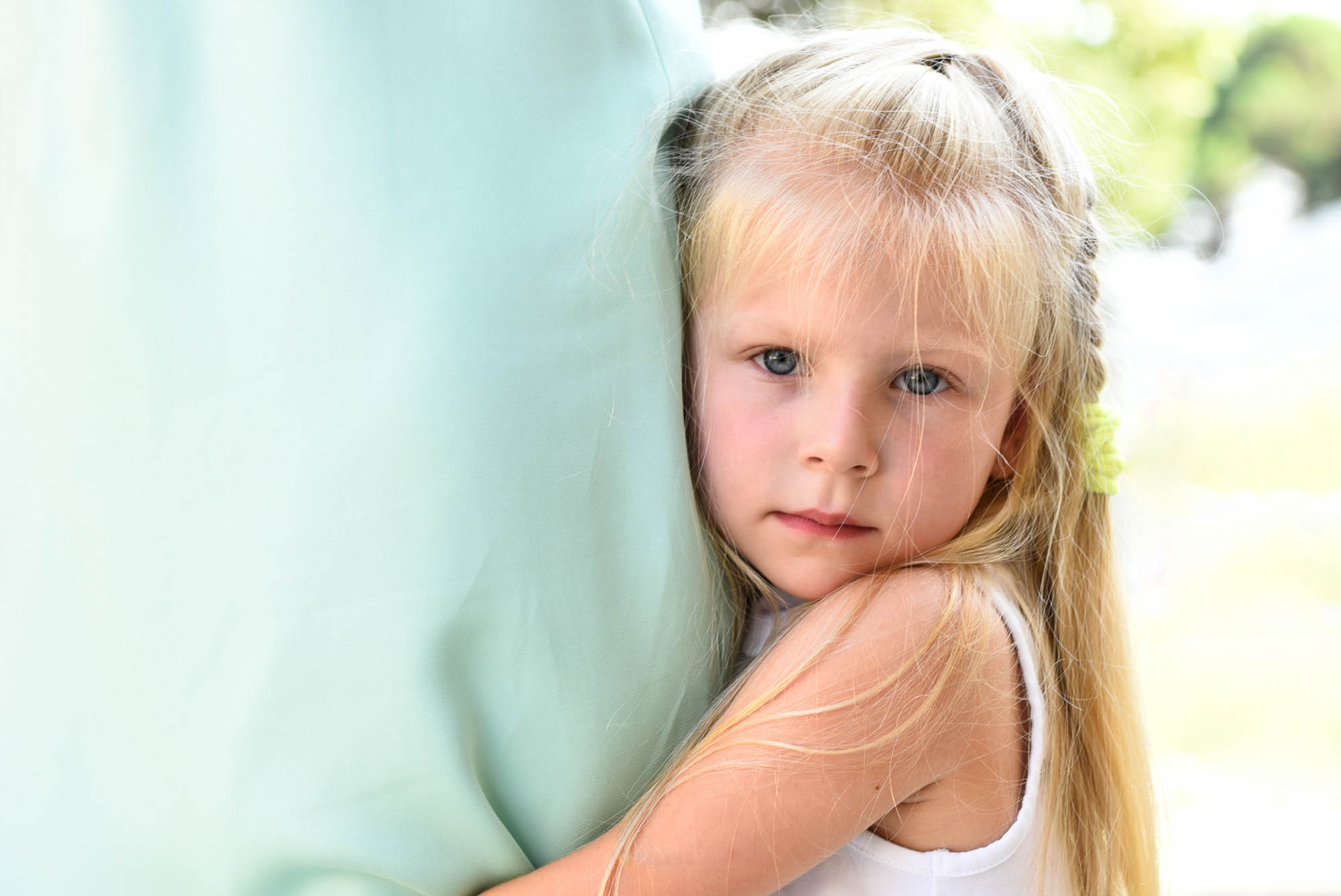 Foto di una bellissima bambina bionda che tiene stretta la gamba della sua mamma
