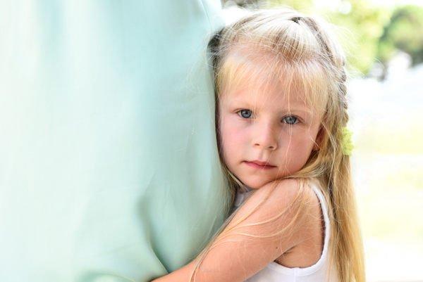 Foto di una bellissima bambina bionda che tiene stretta la gamba della sua mamma