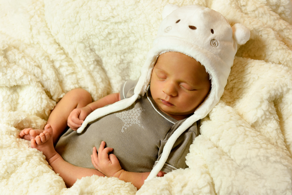 Neonato su copertina lana morbida e cappellino con faccia di orsetto bianco e orecchie