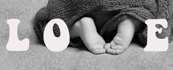 Scritta grafica LOVE con i piedini del neonato che formano la lettera V della scritta. bianco e nero