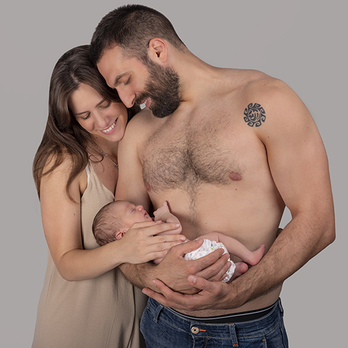 una coppia felice che guarda il figlio in braccio al papà con amore